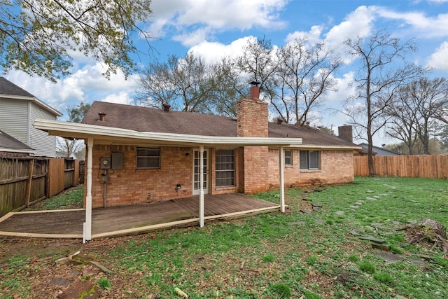 back of property with a yard, a deck, a fenced backyard, and a chimney