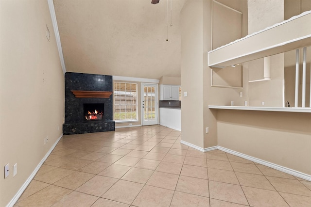 unfurnished living room featuring tile patterned flooring, a ceiling fan, baseboards, and a high end fireplace