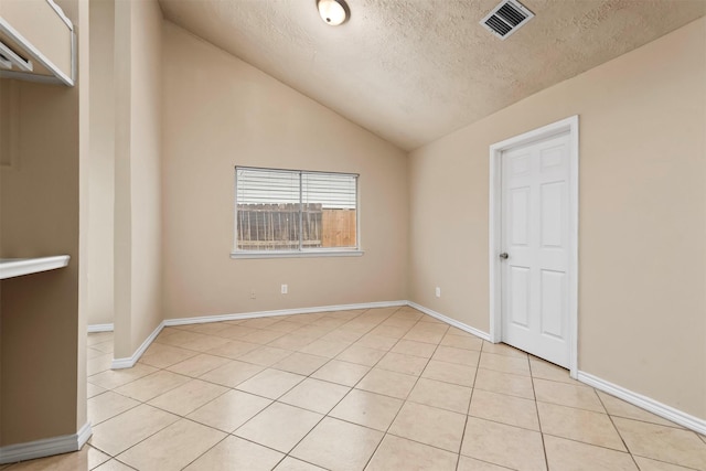 spare room with vaulted ceiling, baseboards, visible vents, and a textured ceiling