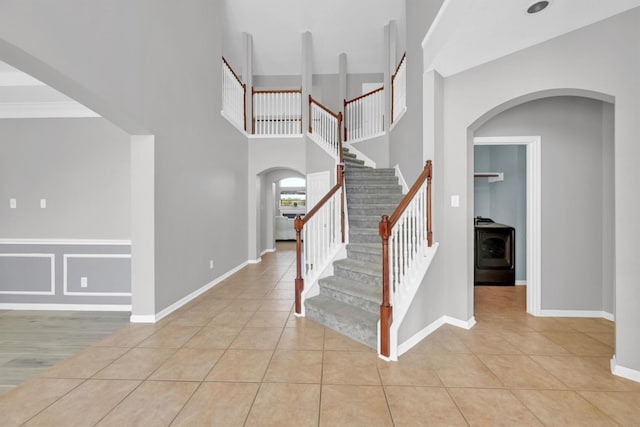 entrance foyer featuring baseboards, stairs, arched walkways, tile patterned floors, and washer / clothes dryer