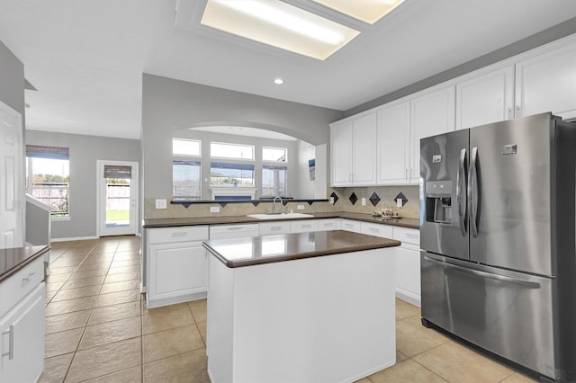 kitchen with a sink, tasteful backsplash, dark countertops, and stainless steel fridge with ice dispenser