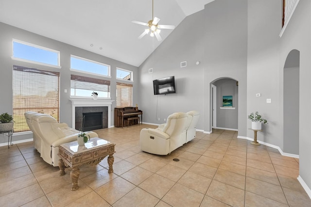 living room with visible vents, baseboards, light tile patterned floors, a tile fireplace, and arched walkways