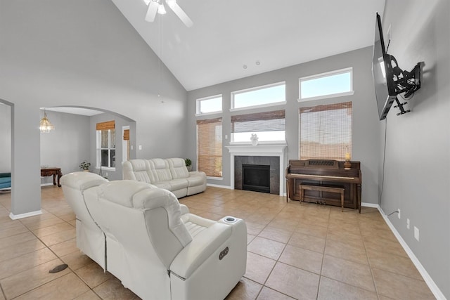 living room with light tile patterned floors, baseboards, arched walkways, and a tile fireplace