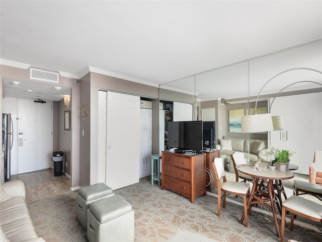 living area featuring visible vents, crown molding, and light wood finished floors