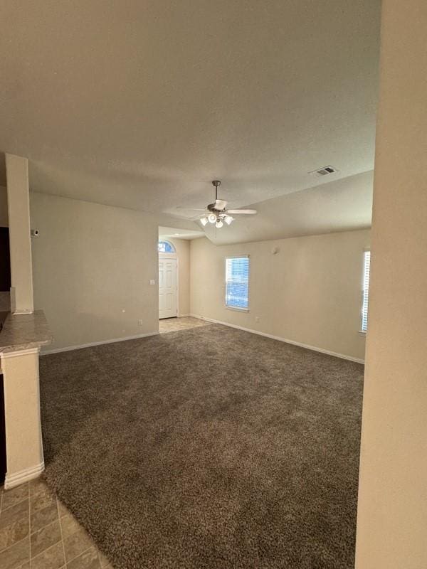 carpeted empty room featuring a textured ceiling, baseboards, visible vents, and ceiling fan