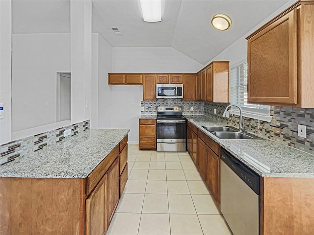 kitchen with a sink, stainless steel appliances, brown cabinetry, light tile patterned floors, and decorative backsplash