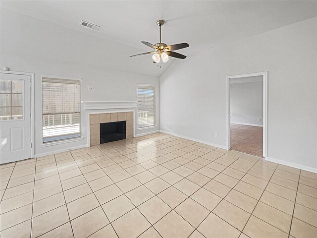 unfurnished living room featuring light tile patterned floors, visible vents, lofted ceiling, ceiling fan, and a tiled fireplace