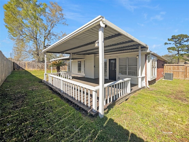 back of house featuring a fenced backyard, central AC, and a yard