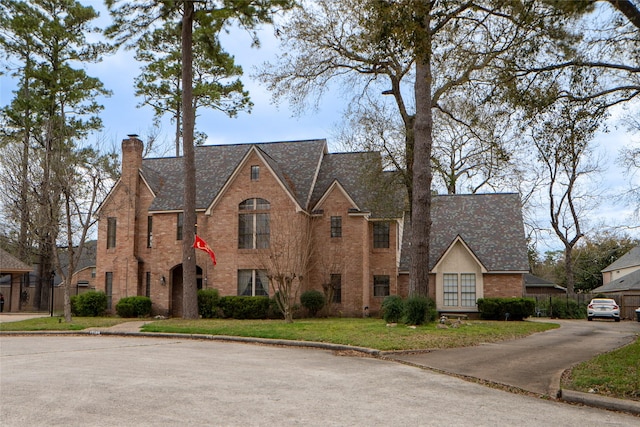 view of front of house with a front yard, brick siding, and a chimney