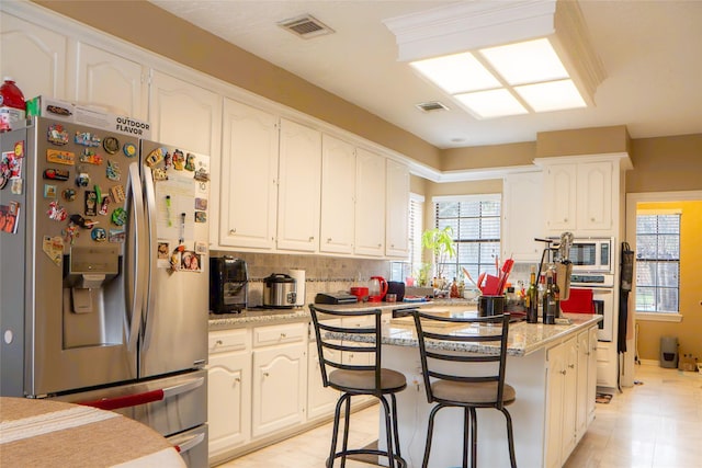 kitchen with backsplash, visible vents, appliances with stainless steel finishes, and a center island