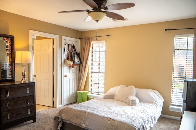 bedroom featuring a ceiling fan, light colored carpet, visible vents, and baseboards