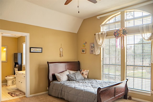 bedroom with a ceiling fan, baseboards, ensuite bath, light tile patterned flooring, and vaulted ceiling