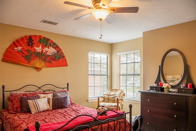 bedroom with a ceiling fan, visible vents, and a textured ceiling