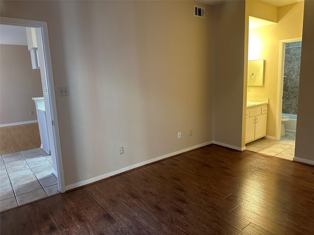 unfurnished bedroom featuring visible vents, light wood-style flooring, ensuite bathroom, and baseboards