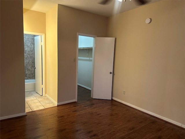 unfurnished bedroom with a closet, baseboards, wood finished floors, and a spacious closet