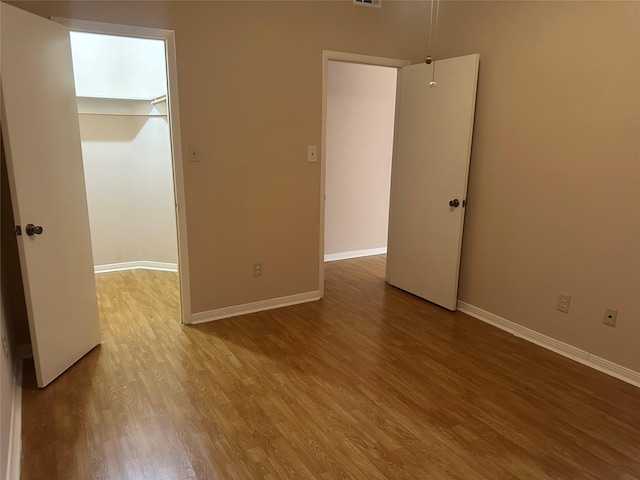 unfurnished room with visible vents, wood finished floors, and baseboards