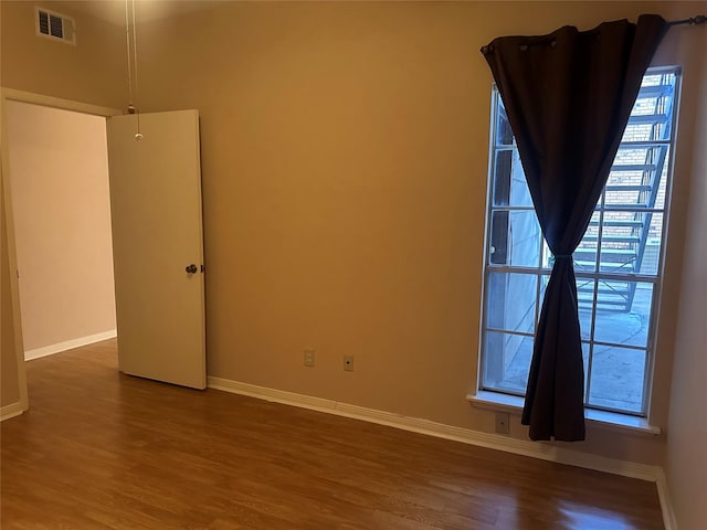 spare room featuring visible vents, baseboards, and dark wood-style flooring