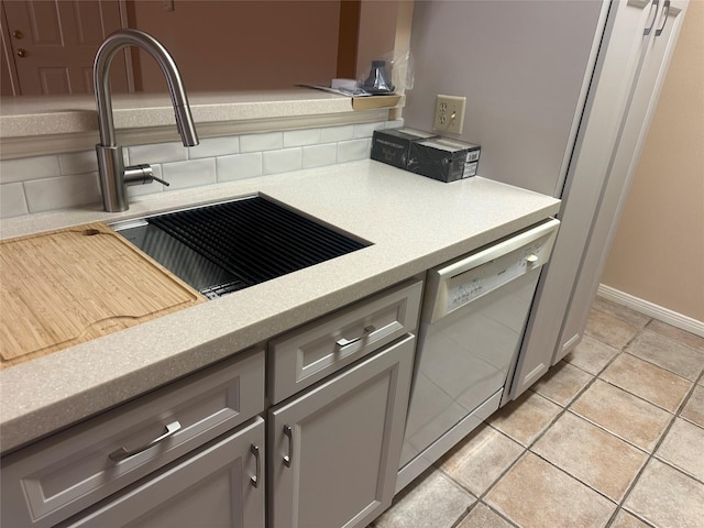 kitchen with dishwasher, light countertops, gray cabinetry, and a sink