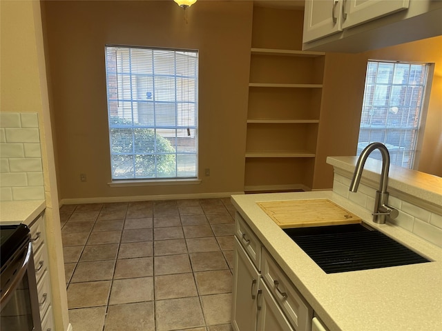 kitchen with light countertops, white cabinets, light tile patterned floors, and a sink