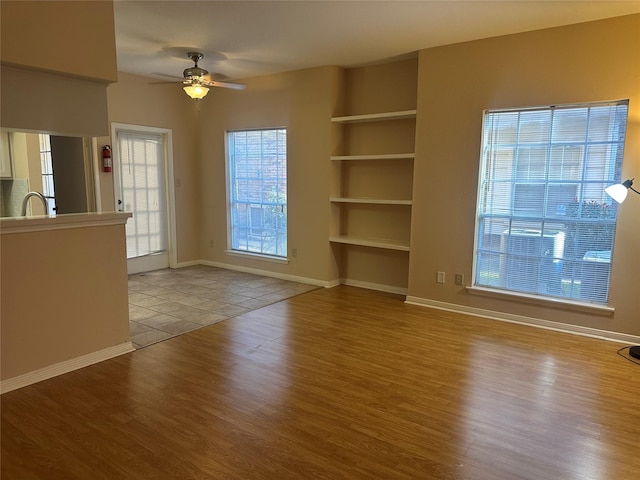 unfurnished living room featuring baseboards, wood finished floors, and a ceiling fan