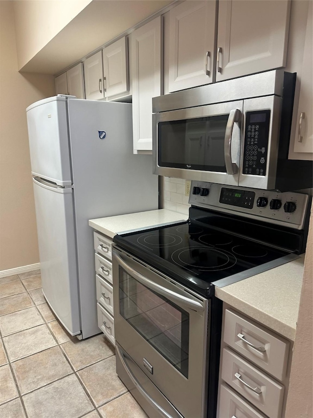 kitchen with baseboards, light tile patterned flooring, stainless steel appliances, light countertops, and backsplash