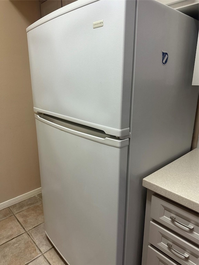 interior details featuring light countertops, baseboards, freestanding refrigerator, and gray cabinetry