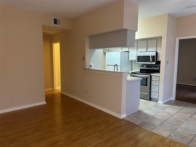 kitchen with light wood finished floors, visible vents, baseboards, light countertops, and appliances with stainless steel finishes