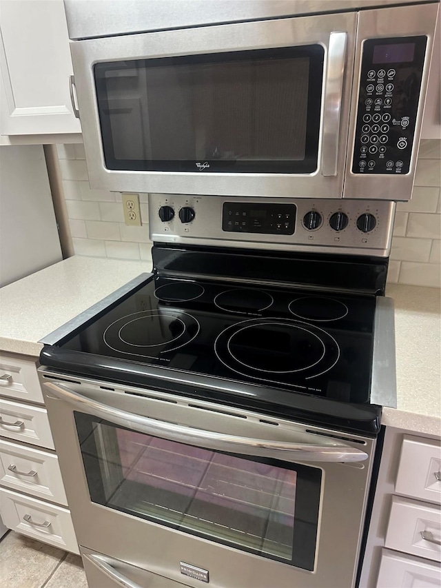 kitchen with white cabinetry, light countertops, decorative backsplash, and stainless steel appliances