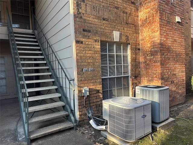 exterior details featuring brick siding, central air condition unit, and stairway