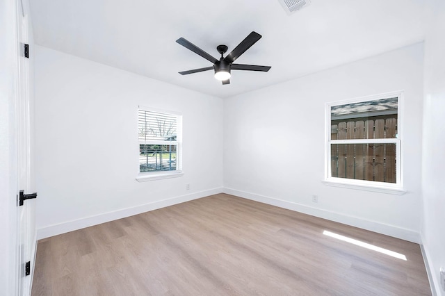 unfurnished room featuring ceiling fan, visible vents, baseboards, and wood finished floors