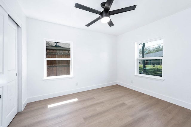 spare room featuring light wood-style flooring, baseboards, and ceiling fan