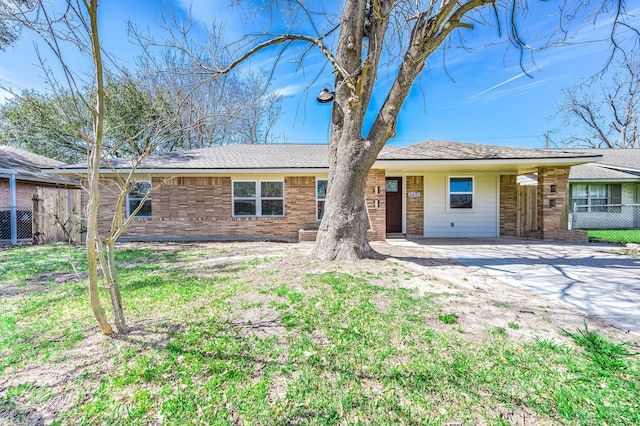 view of front of house with brick siding, driveway, and fence