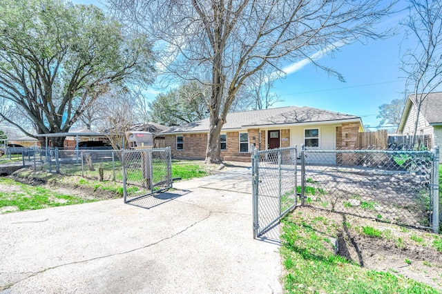 ranch-style home with a fenced front yard, concrete driveway, brick siding, and a gate