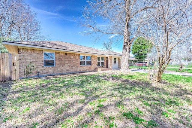 view of front facade with brick siding, a front lawn, and fence