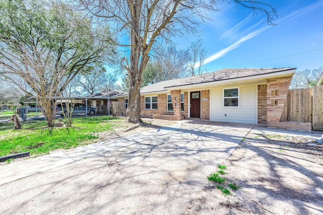 ranch-style home featuring brick siding, driveway, and fence