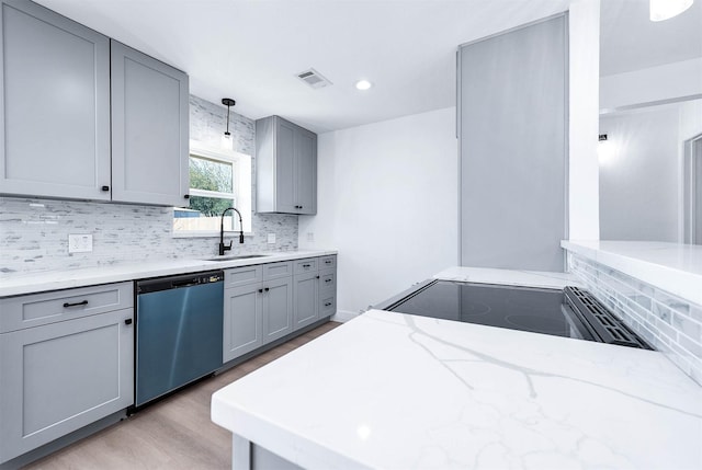 kitchen with light stone counters, dishwashing machine, gray cabinets, and a sink