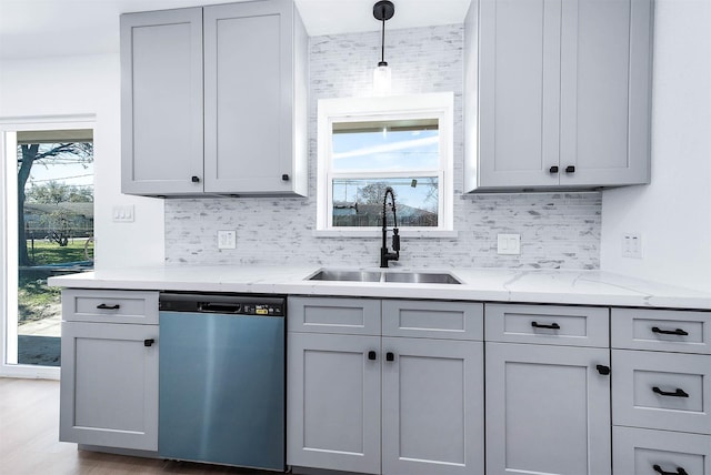 kitchen featuring dishwashing machine, gray cabinetry, backsplash, and a sink