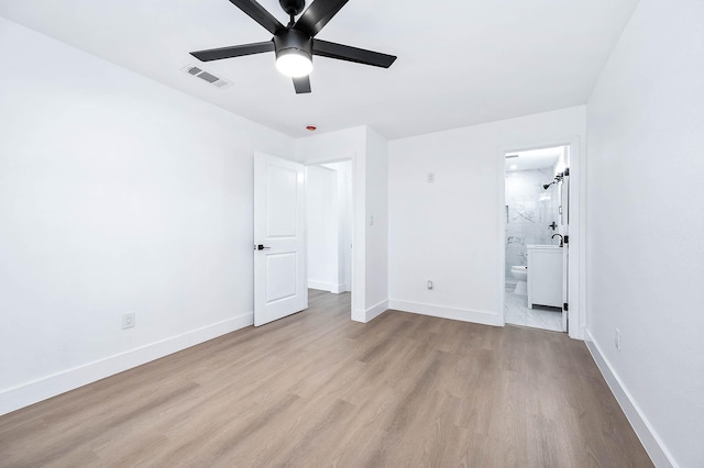 unfurnished bedroom featuring visible vents, ensuite bathroom, baseboards, and wood finished floors