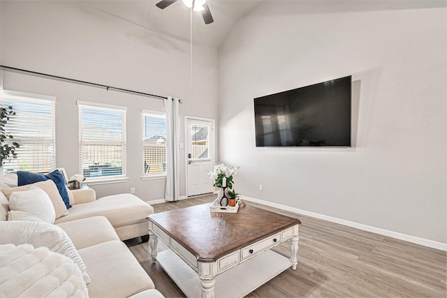 living area with vaulted ceiling, wood finished floors, baseboards, and ceiling fan