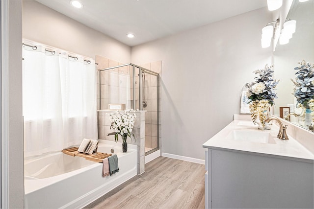 full bath with a shower stall, a bath, wood finished floors, and a sink