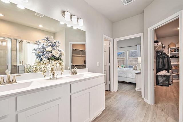 bathroom with visible vents, a shower stall, wood finished floors, and a sink