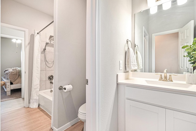 bathroom featuring baseboards, shower / bath combo with shower curtain, toilet, wood finished floors, and vanity