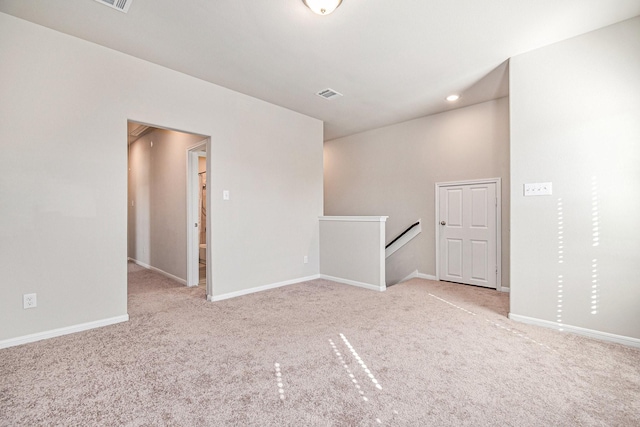 spare room with baseboards, visible vents, and light carpet