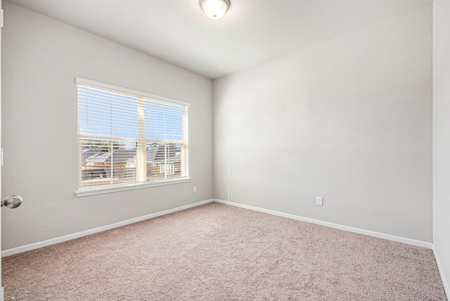 carpeted empty room featuring baseboards