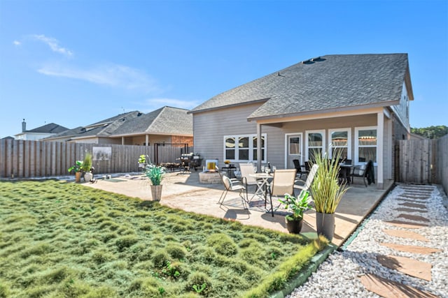 rear view of property featuring a patio area, a lawn, a fenced backyard, and roof with shingles