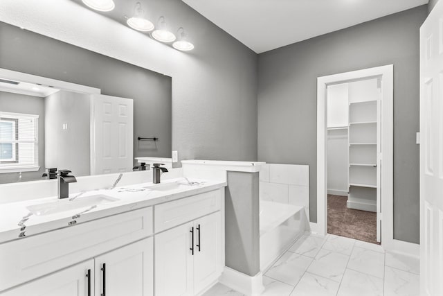 bathroom with double vanity, marble finish floor, a garden tub, and a sink