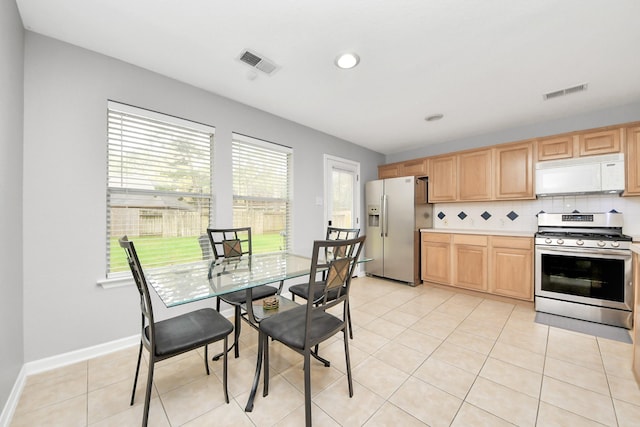 kitchen featuring light brown cabinetry, visible vents, stainless steel appliances, and decorative backsplash