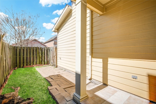 view of side of property featuring a patio area, a fenced backyard, and a lawn