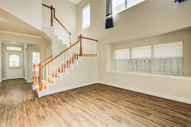 entrance foyer with a high ceiling, stairway, wood finished floors, and baseboards