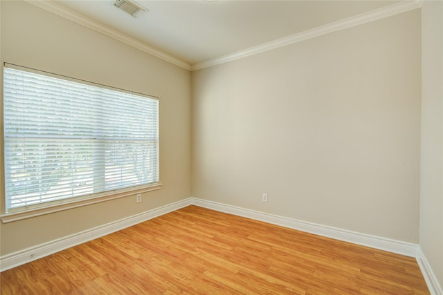 unfurnished room featuring visible vents, light wood-type flooring, baseboards, and ornamental molding